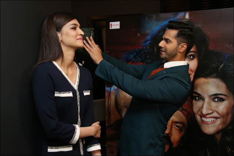 Varun Dhawan takes a selfie as Kriti Sanon, left looks on