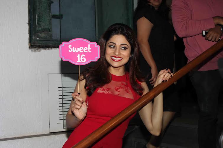 Shamita Shetty in red with a sweet sixteen placard